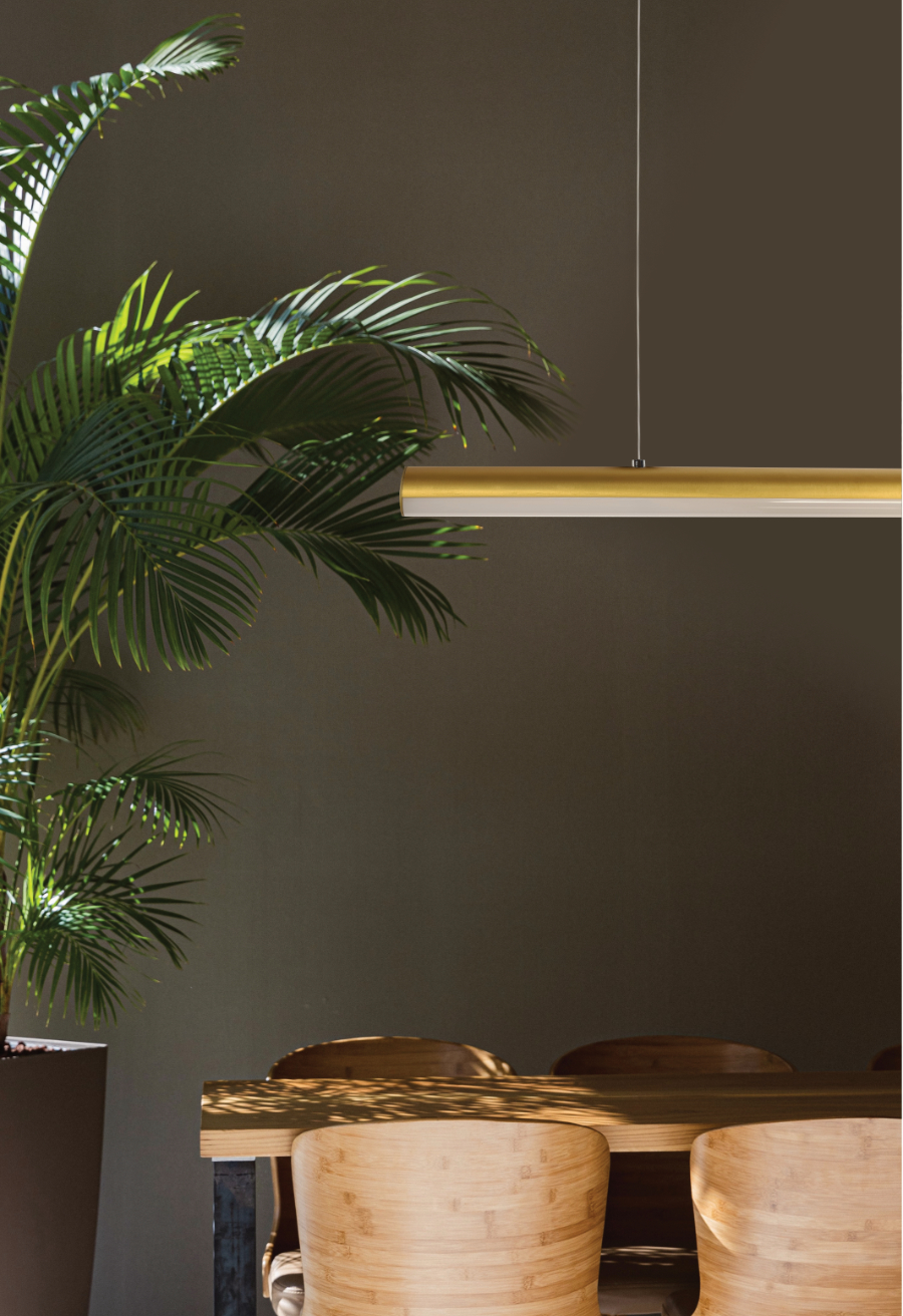 A brushed brass dowel LED linear pendant suspended over a timber table